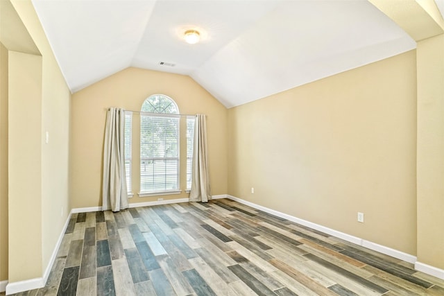 spare room with vaulted ceiling and hardwood / wood-style flooring