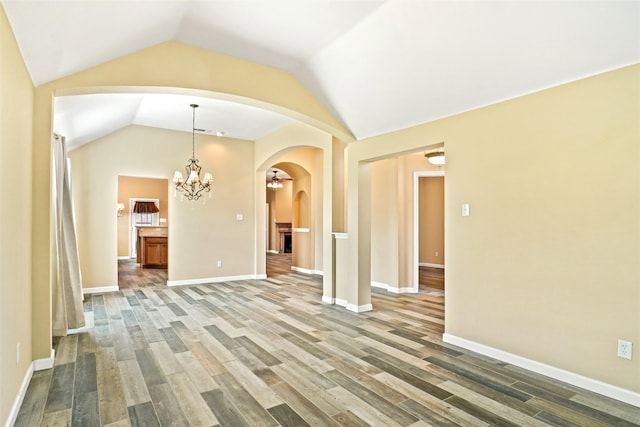 unfurnished living room with lofted ceiling, hardwood / wood-style flooring, and a chandelier