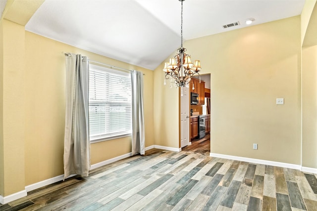 unfurnished dining area featuring wood-type flooring, lofted ceiling, and a notable chandelier