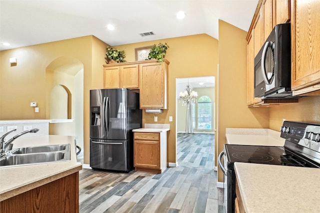 kitchen with hardwood / wood-style flooring, sink, black appliances, a chandelier, and vaulted ceiling