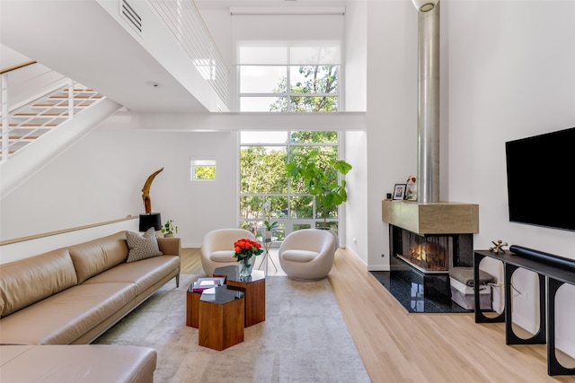 living room with a fireplace, light hardwood / wood-style floors, and a high ceiling