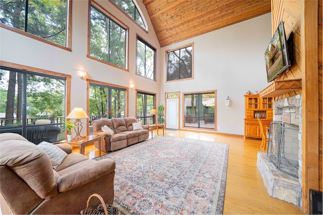 living room featuring high vaulted ceiling, plenty of natural light, light hardwood / wood-style floors, and a fireplace