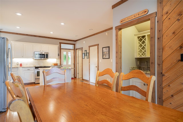 dining area with sink, light hardwood / wood-style floors, and crown molding