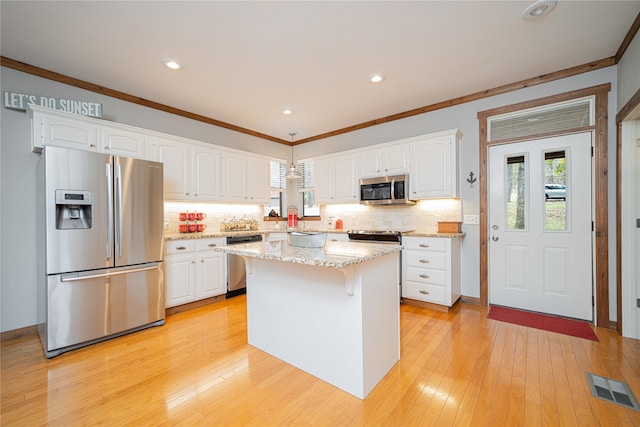 kitchen with white cabinetry, stainless steel appliances, a center island, and decorative light fixtures