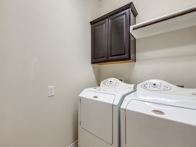 clothes washing area with cabinets and washer and dryer