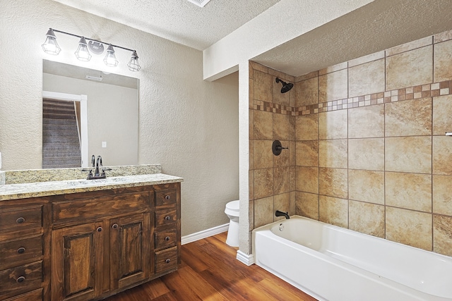 bathroom with shower / bathing tub combination, toilet, vanity, a textured ceiling, and wood finished floors