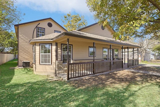 view of front of home featuring covered porch, fence, a front lawn, and central AC unit