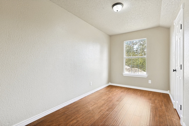 unfurnished bedroom with a textured ceiling, baseboards, wood finished floors, and a textured wall