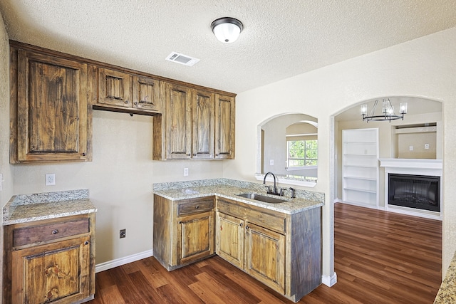 kitchen featuring dark wood-style floors, a sink, visible vents, and brown cabinets