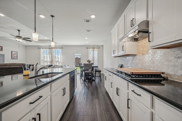 kitchen with stainless steel appliances, white cabinets, sink, dark hardwood / wood-style floors, and decorative light fixtures