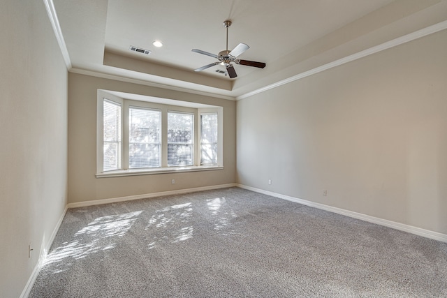 carpeted empty room featuring ceiling fan, ornamental molding, and a tray ceiling