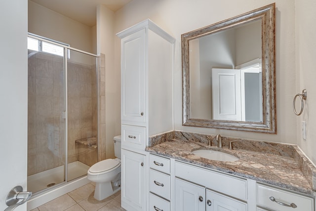 bathroom featuring toilet, tile patterned floors, vanity, and a shower with door