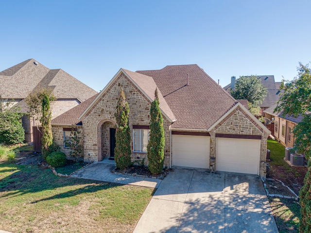 view of front of property featuring a garage, cooling unit, and a front yard