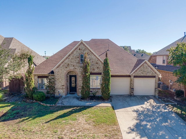 view of front of home with a garage, cooling unit, and a front yard