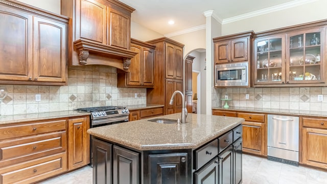 kitchen with sink, a kitchen island with sink, appliances with stainless steel finishes, and tasteful backsplash