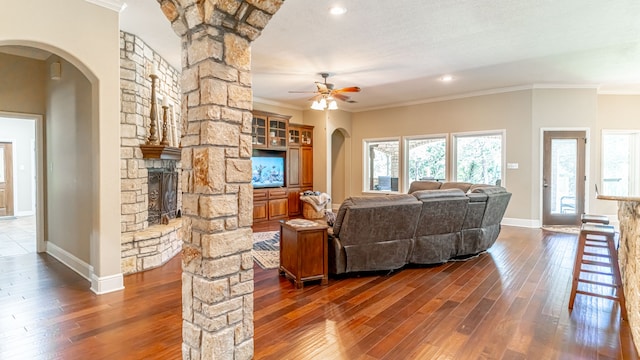 living room with ornamental molding, ceiling fan, dark hardwood / wood-style floors, and a fireplace