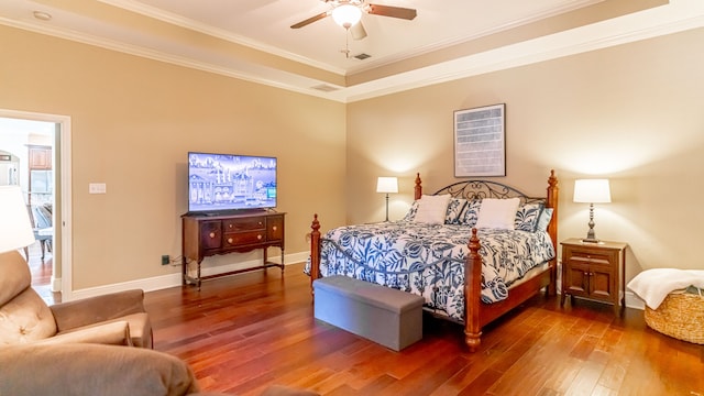 bedroom featuring dark wood-type flooring, ceiling fan, a tray ceiling, and ornamental molding