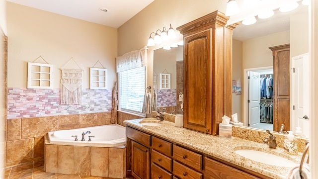 bathroom with a relaxing tiled tub, vanity, and tile patterned floors