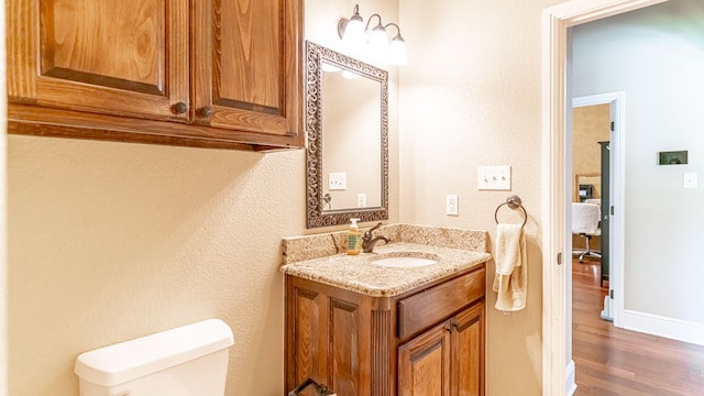 bathroom featuring toilet, vanity, and hardwood / wood-style flooring