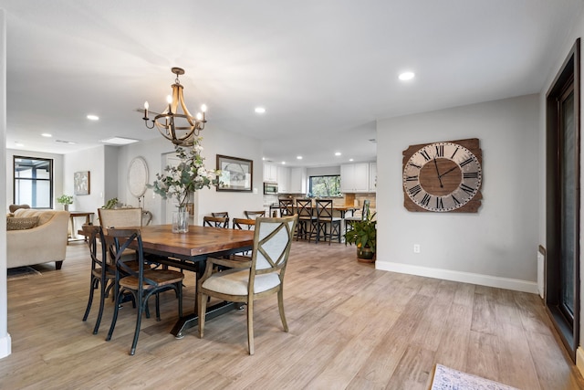 dining space with light wood-type flooring and an inviting chandelier