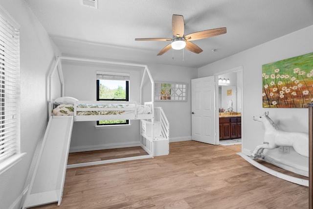 bedroom featuring light wood-type flooring, ceiling fan, and ensuite bathroom