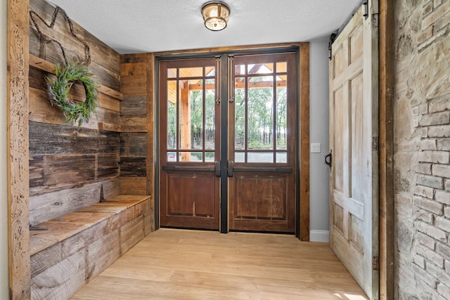 entryway with light hardwood / wood-style flooring, a barn door, french doors, and a textured ceiling