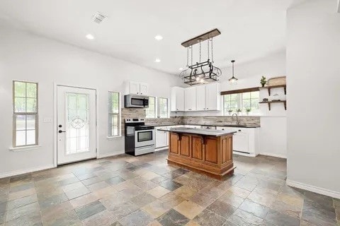 kitchen featuring an inviting chandelier, hanging light fixtures, white electric stove, a center island, and white cabinets