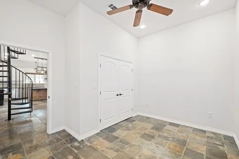 unfurnished room featuring ceiling fan and a towering ceiling