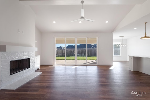 unfurnished living room with ceiling fan, a stone fireplace, dark wood-type flooring, and vaulted ceiling