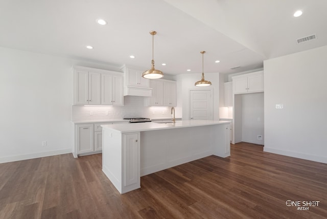 kitchen featuring pendant lighting, white cabinetry, and a kitchen island with sink