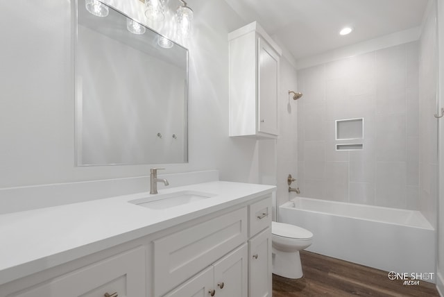 full bathroom featuring vanity, tiled shower / bath combo, hardwood / wood-style flooring, and toilet