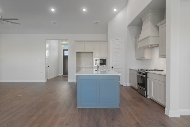 kitchen featuring dark wood-type flooring, sink, ceiling fan, an island with sink, and appliances with stainless steel finishes