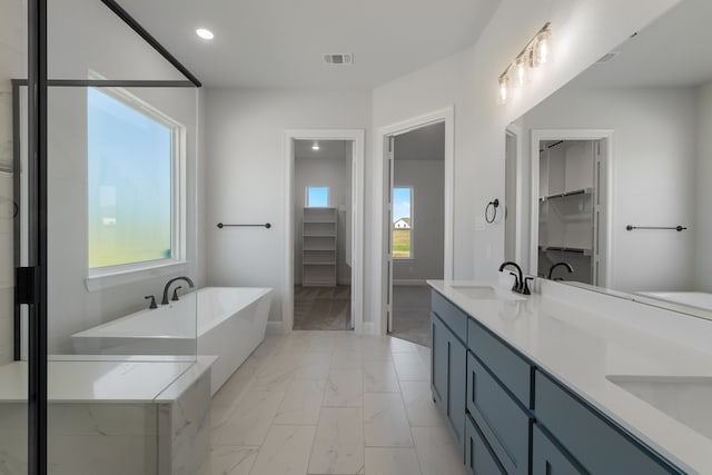 bathroom featuring a relaxing tiled tub and vanity