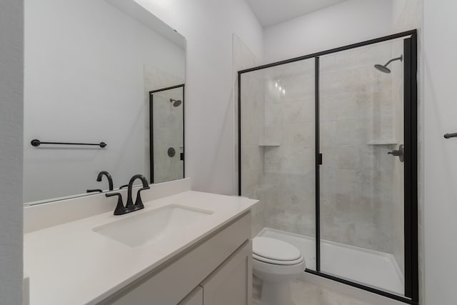 bathroom featuring vanity, a shower with shower door, and toilet