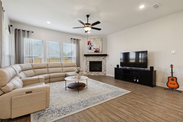 living room with hardwood / wood-style flooring, ceiling fan, and a fireplace