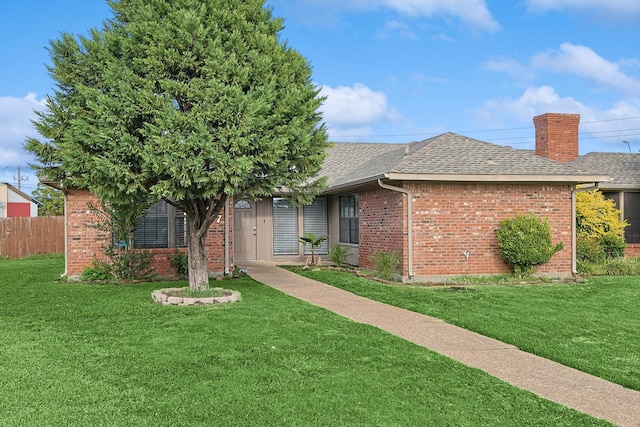 ranch-style house featuring a chimney, brick siding, roof with shingles, and a front yard