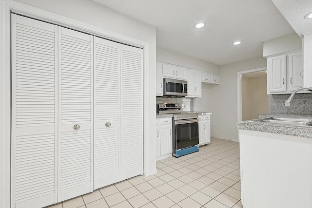 kitchen featuring appliances with stainless steel finishes, white cabinetry, light countertops, and a sink