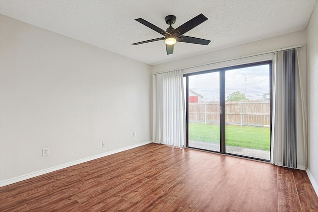 spare room featuring baseboards, a textured ceiling, and wood finished floors