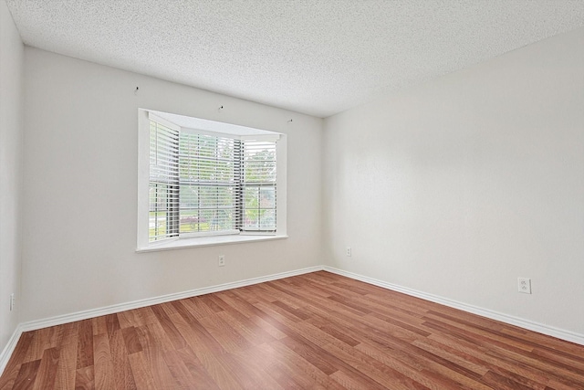 empty room featuring wood finished floors, baseboards, and a textured ceiling