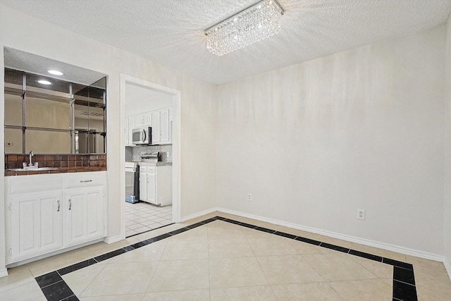 interior space with a sink, a textured ceiling, recessed lighting, light tile patterned floors, and baseboards