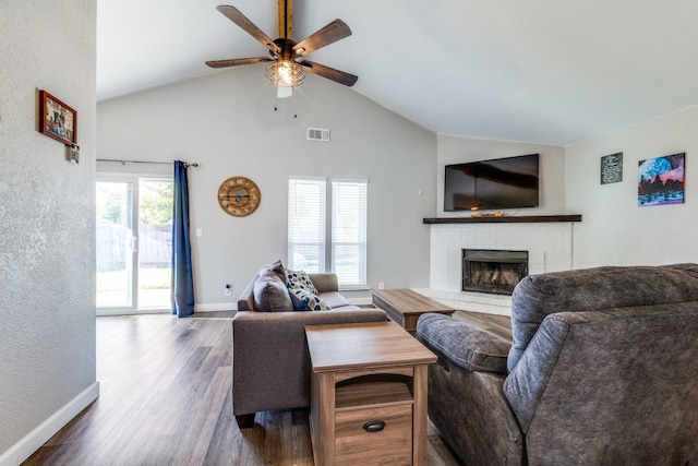 living room featuring dark wood-type flooring, lofted ceiling, ceiling fan, and a fireplace