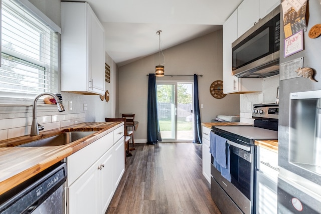 kitchen with sink, appliances with stainless steel finishes, lofted ceiling, white cabinets, and pendant lighting