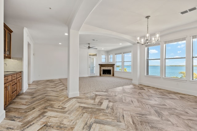 unfurnished living room featuring arched walkways, recessed lighting, a fireplace, visible vents, and baseboards