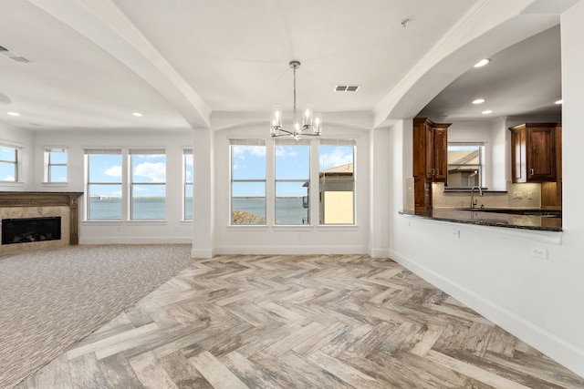 unfurnished living room featuring arched walkways, visible vents, a chandelier, and baseboards