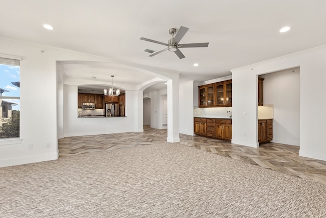 unfurnished living room featuring light parquet flooring, ceiling fan with notable chandelier, and crown molding