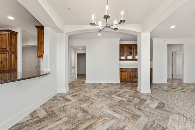 unfurnished living room with light parquet floors, a notable chandelier, and ornamental molding