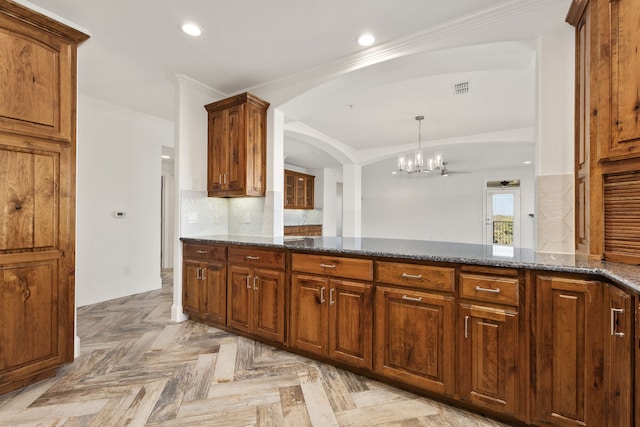 kitchen with ornamental molding, dark stone countertops, an inviting chandelier, light parquet floors, and pendant lighting