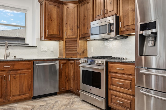 500 Waters Edge Dr Unit 239, Lake Dallas, TX 75065 - kitchen with appliances with stainless steel finishes, a sink, decorative backsplash, dark stone counters, and brown cabinets
