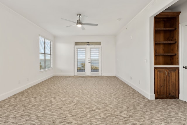 unfurnished room with french doors, ceiling fan, crown molding, and light colored carpet