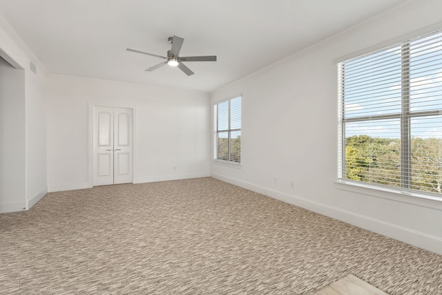 empty room with ceiling fan, a healthy amount of sunlight, carpet flooring, and crown molding